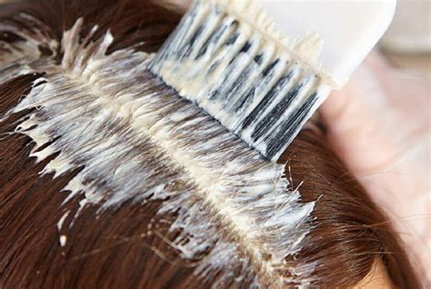Mujer aplicándose tinte para el cabello en casa