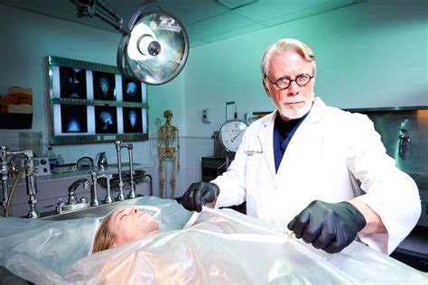 Un médico forense examinando los cuerpos de Manny Escuela y Jay Hamilton.