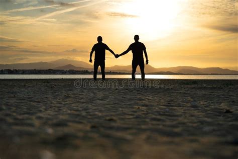 Dos hombres tomados de la mano en un atardecer
