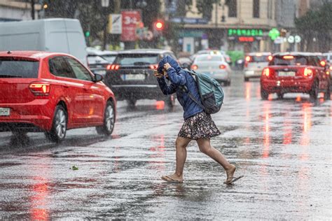 Una mujer de pie bajo la lluvia frente a una tumba