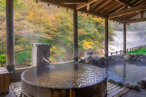 Hombre relajándose en un onsen japonés rodeado de naturaleza