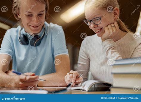 Dos estudiantes trabajando juntos en un proyecto escolar, uno con expresión de frustración y el otro con una sonrisa