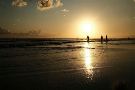 Atardecer en una playa con siluetas de dos personas