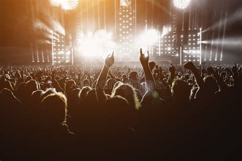 Imagen de un concierto de rock con luces dramáticas y una multitud entusiasta.