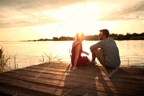 Pareja conversando junto a un lago al atardecer