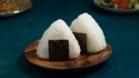 Variedad de onigiris con diferentes formas y rellenos, incluyendo el clásico de umeboshi.