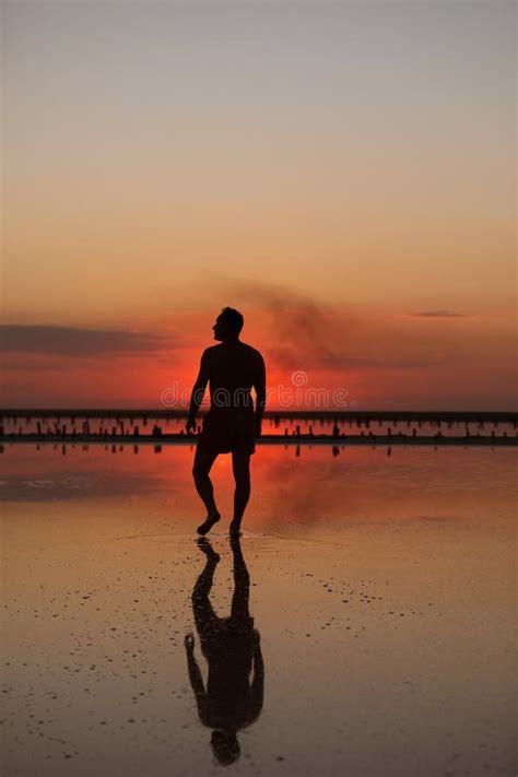 Silueta de un chico bailando junto al mar al atardecer