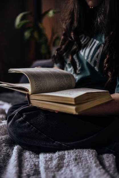 Una mujer con un libro abierto en su regazo, rodeada de naturaleza.