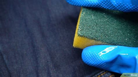 Hombre aplicando lejía con pulverizador en jeans